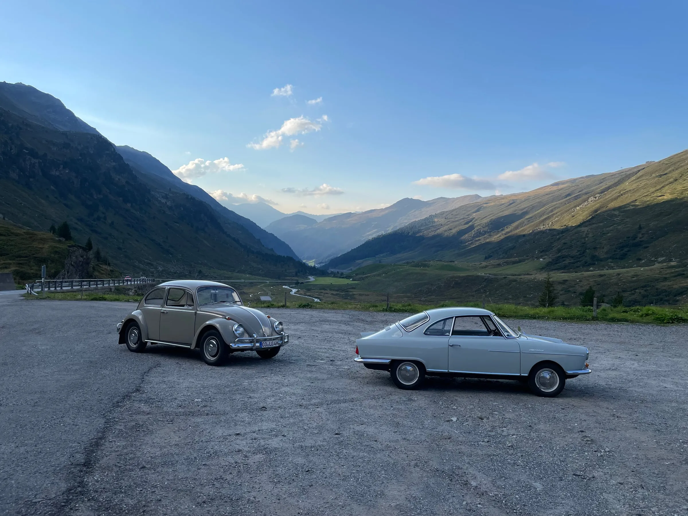 VW Käfer und NSU Sprint auf einem Alpenpass vor der Bergkulisse
